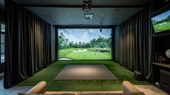 A golf simulator room with a screen showing a golf course.