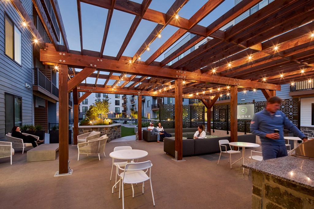 A man is standing in a patio with a table and chairs.