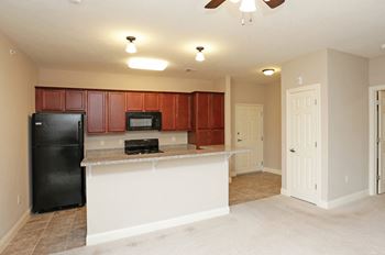 A kitchen with brown cabinets and a black refrigerator.