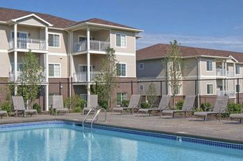A swimming pool is in front of apartment buildings.