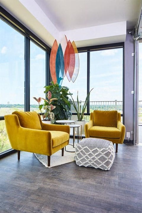 two yellow chairs in a living room with large windows