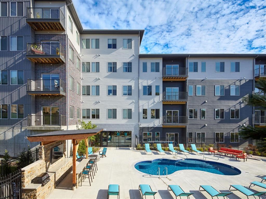 a large swimming pool with chaise lounge chairs and a building in the background