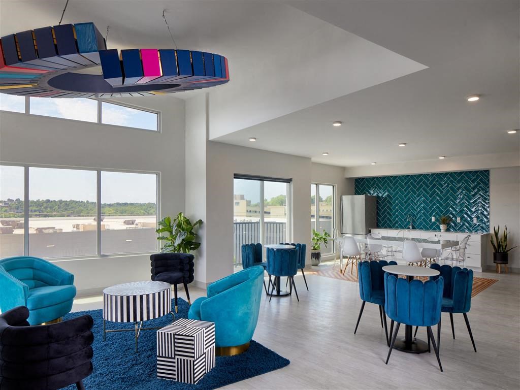 a lounge area with blue chairs and tables and a large window