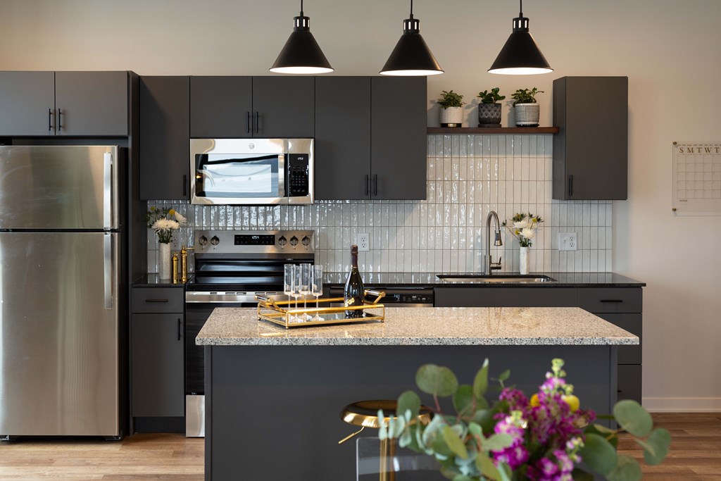 A modern kitchen with a granite countertop and stainless steel appliances.