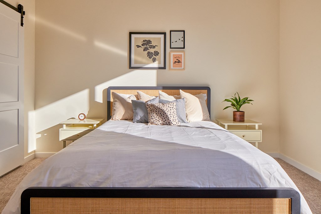 a bedroom with a bed and a night stand with a potted plant