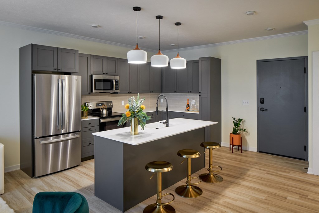 a kitchen with stainless steel appliances and a large island with three stools