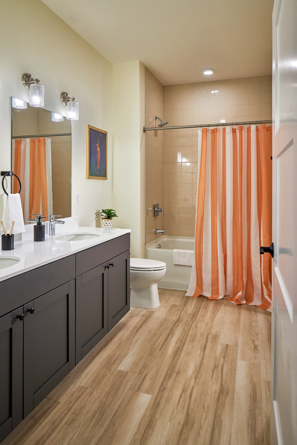 a bathroom with an orange shower curtain and a toilet and sink