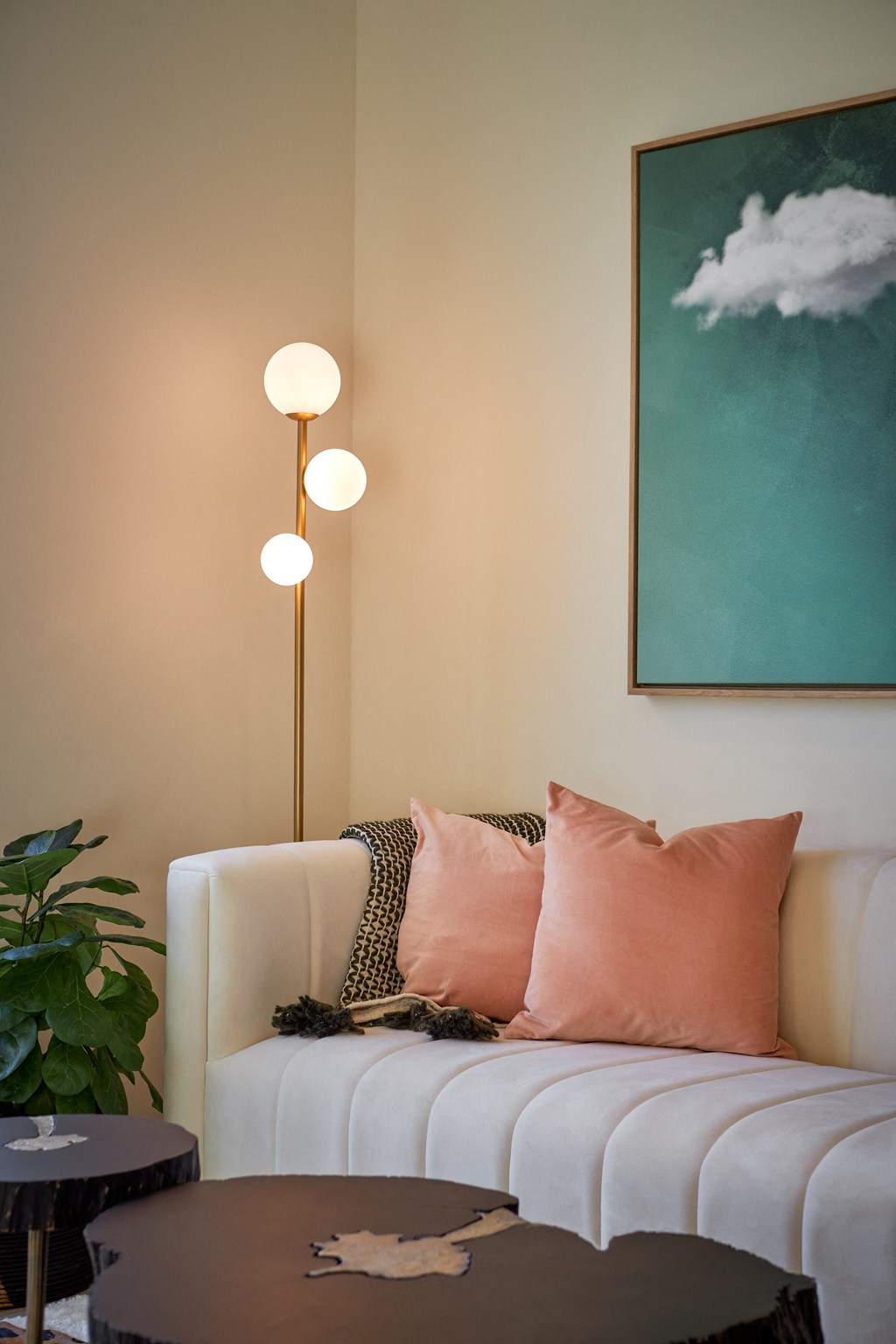 a living room with a white couch and pink pillows and a green painting