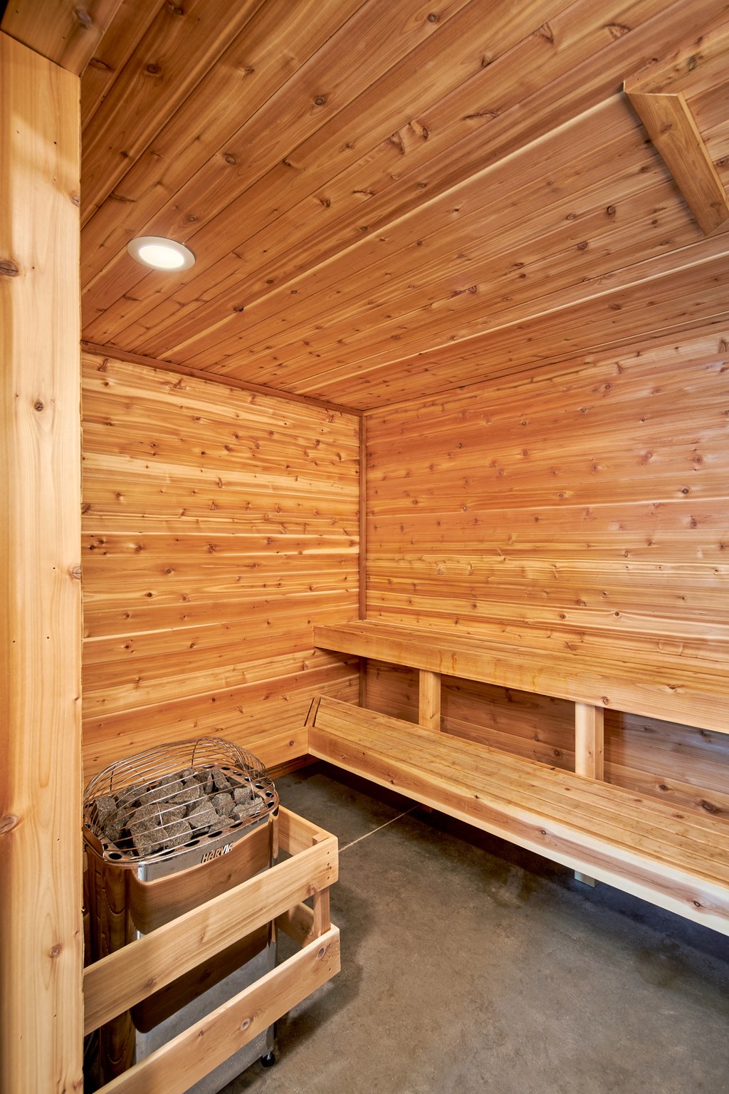 a large sauna with a bench and a bucket of wood