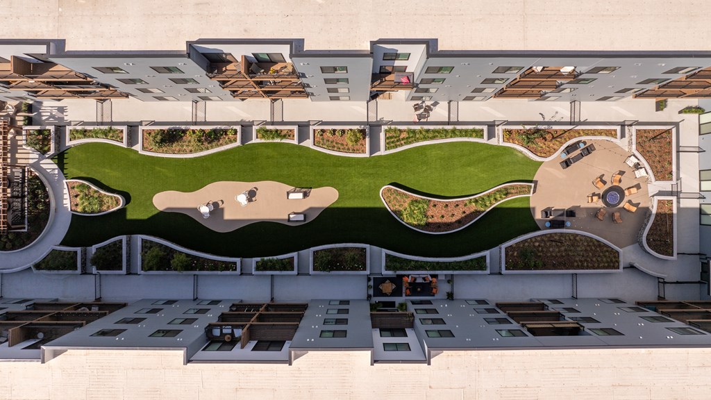 A top-down view of a building with a green outdoor area and a parking lot.