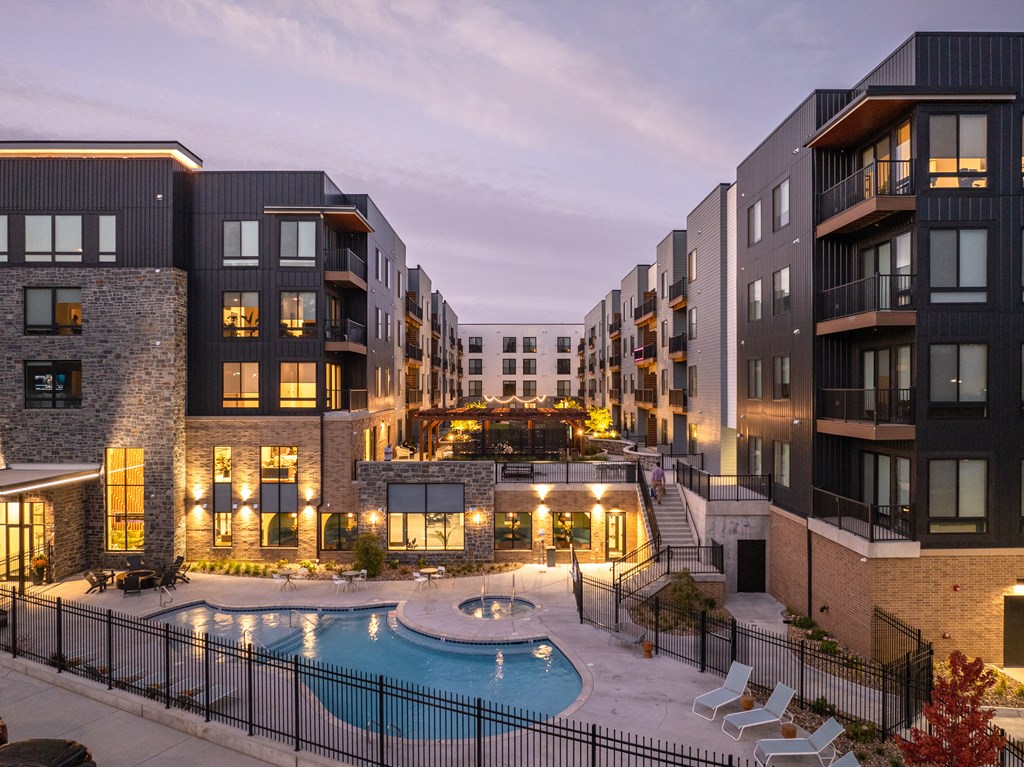 A row of modern apartment buildings with a pool in the courtyard.