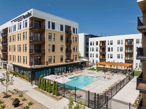 A large apartment complex with a pool in the middle of the courtyard.
