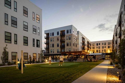 A modern building complex with a grassy area in front.