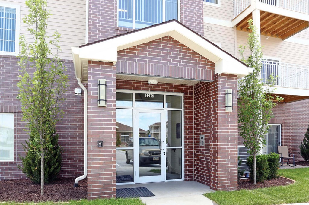 The front of a brick building with a glass door and windows.
