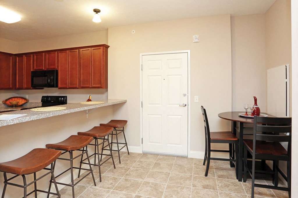 A kitchen with brown bar stools and a white door.