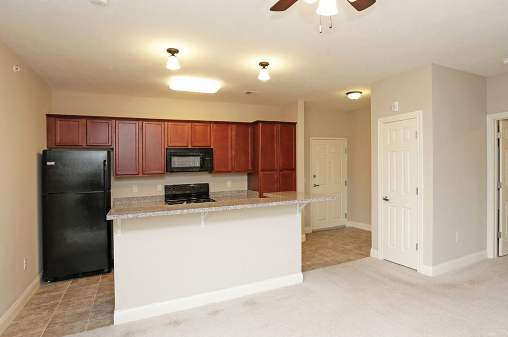 A kitchen with brown cabinets and a black refrigerator.