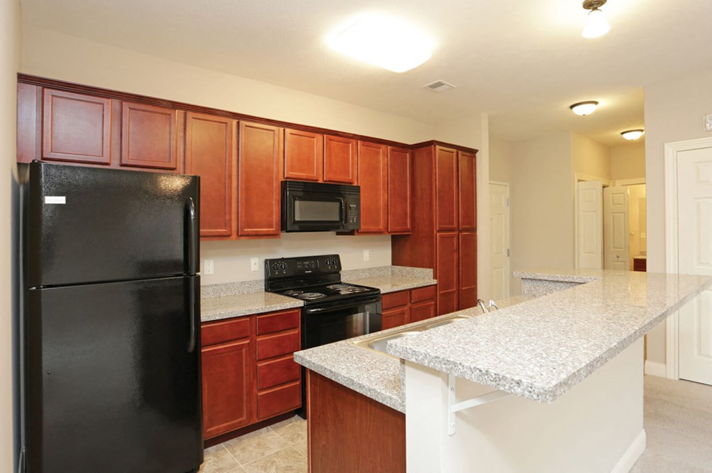 A kitchen with brown cabinets and a black refrigerator.