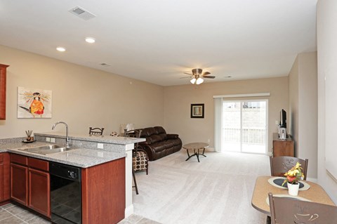 A kitchen with a sink, stove, and a dining table with chairs.
