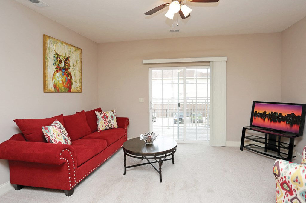 A living room with a red couch and a painting of an owl on the wall.