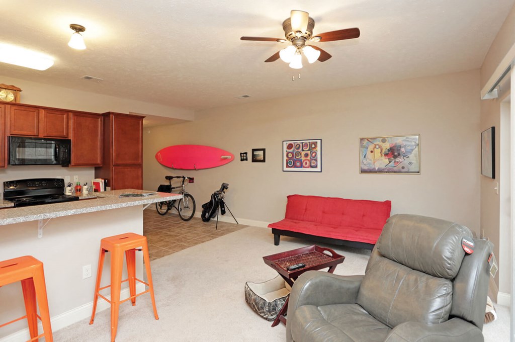 A living room with a red couch and a ceiling fan.