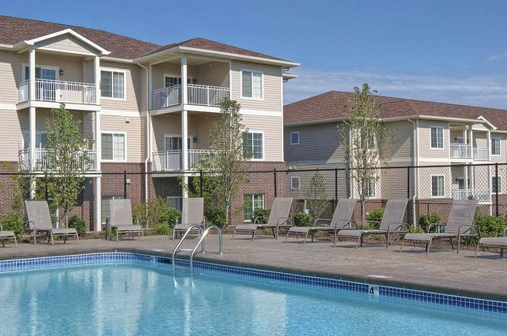 A swimming pool is in front of apartment buildings.
