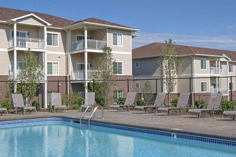 A swimming pool is in front of apartment buildings.