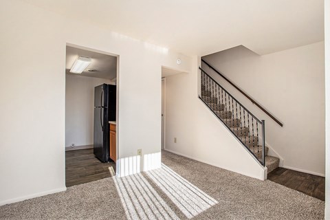 A room with a staircase and a refrigerator.