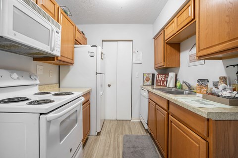 A kitchen with white appliances and wooden cabinets.