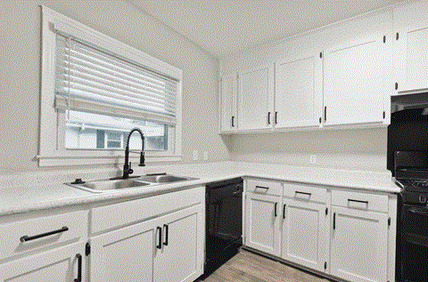 A kitchen with white cabinets and black appliances.