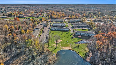 An aerial view of a campus with a lake and autumn trees.