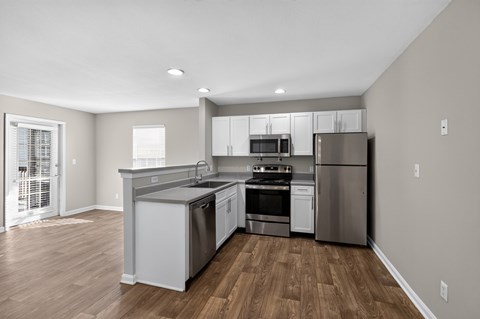 A modern kitchen with stainless steel appliances and wooden floors.