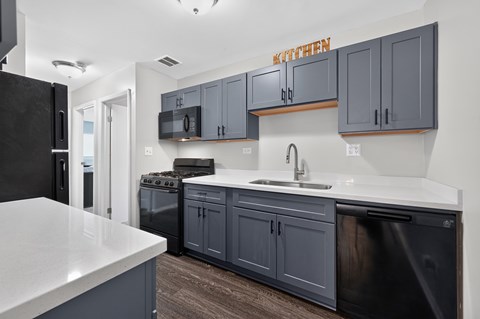 A kitchen with a black refrigerator and cabinets.