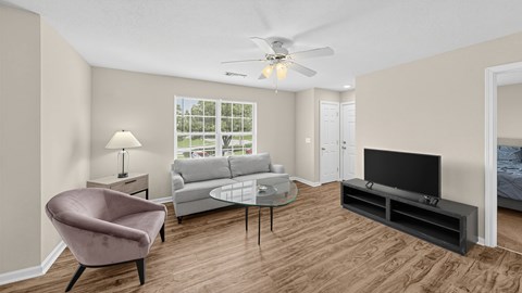 A living room with a television, a chair, a couch, and a table.