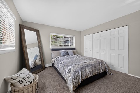 Bedroom at Renaissance at Carol Stream featuring a large bed and wall mirror in Carol Stream, IL.