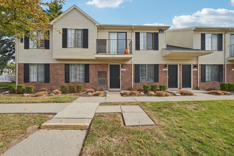 A row of townhouses with a sidewalk in front.