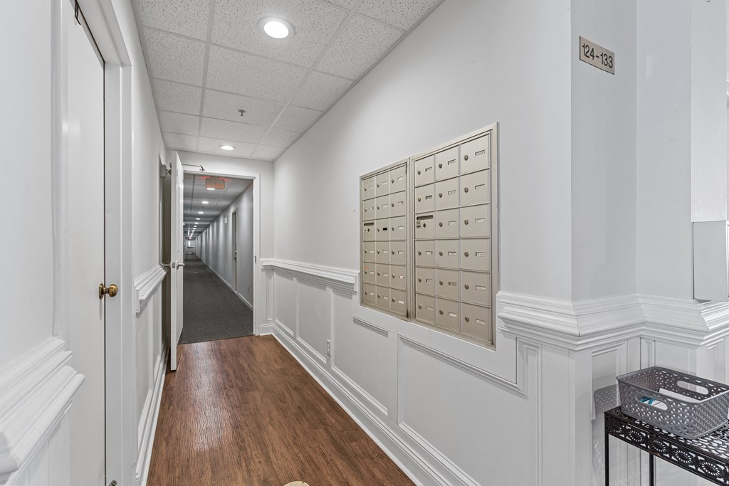 a long white hallway with white walls and a row of lockers on the wall