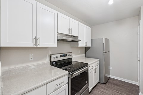 A kitchen with white cabinets and a stove top oven.