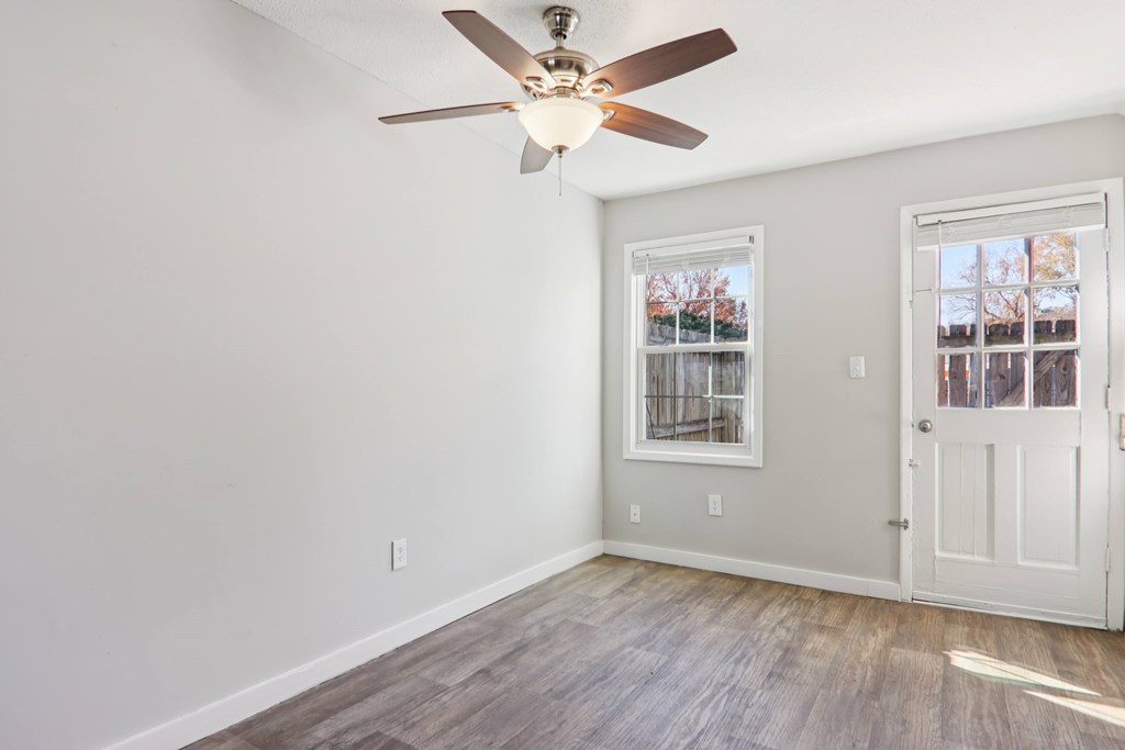 A room with a ceiling fan and a door.