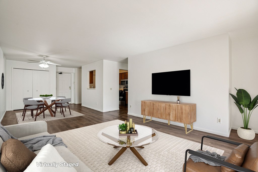 A living room with a white sofa, a wooden coffee table, and a flat screen TV mounted on the wall.