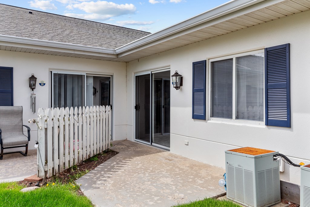 a white house with a white picket fence and a backdoor to a patio