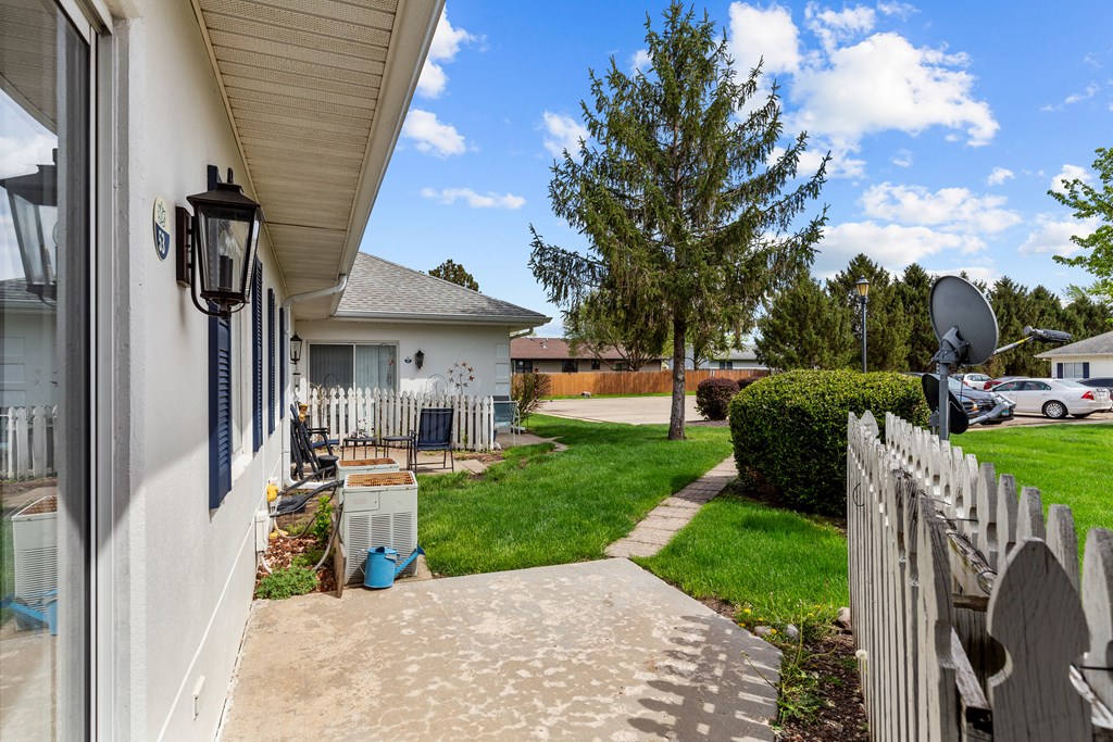 side view of a house with a yard and a sidewalk and a white fence