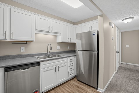 Apartment kitchen with a stainless steel refrigerator and white cabinets at Arbours at Victoria Place in Prattville, AL