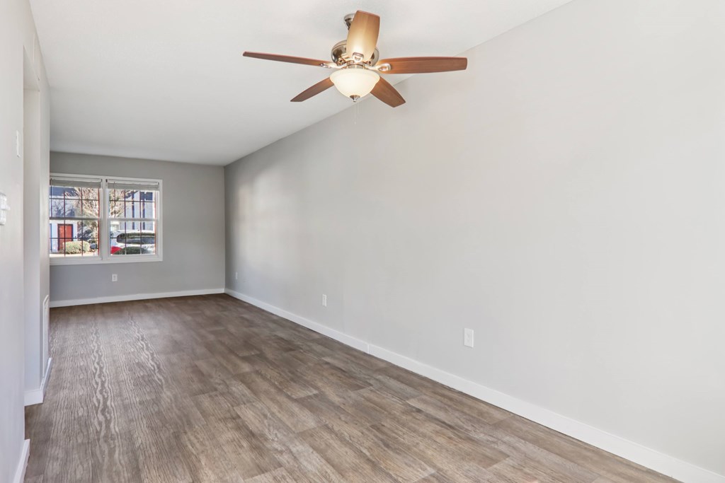 A room with a ceiling fan and wooden flooring.