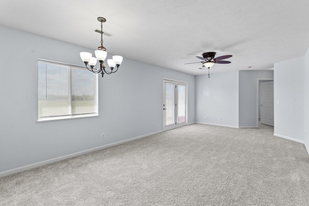 an empty living room with a ceiling fan and a window