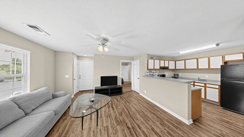 A living room with a grey couch and a glass coffee table.