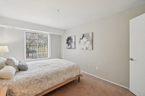 A bedroom with a bed, a lamp, and two pictures on the wall.