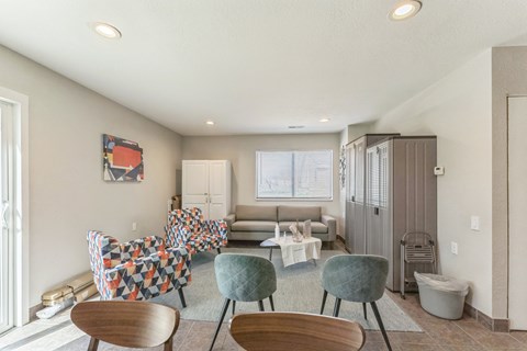 A living room with a couch, chairs, and a painting on the wall.