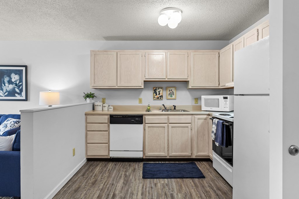 an apartment kitchen with white appliances and wooden cabinets