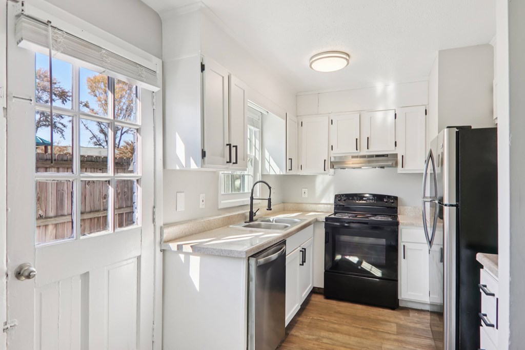 A white kitchen with black appliances and a window.