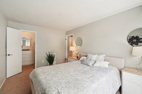 A bedroom with a large bed and a dresser with a mirror.